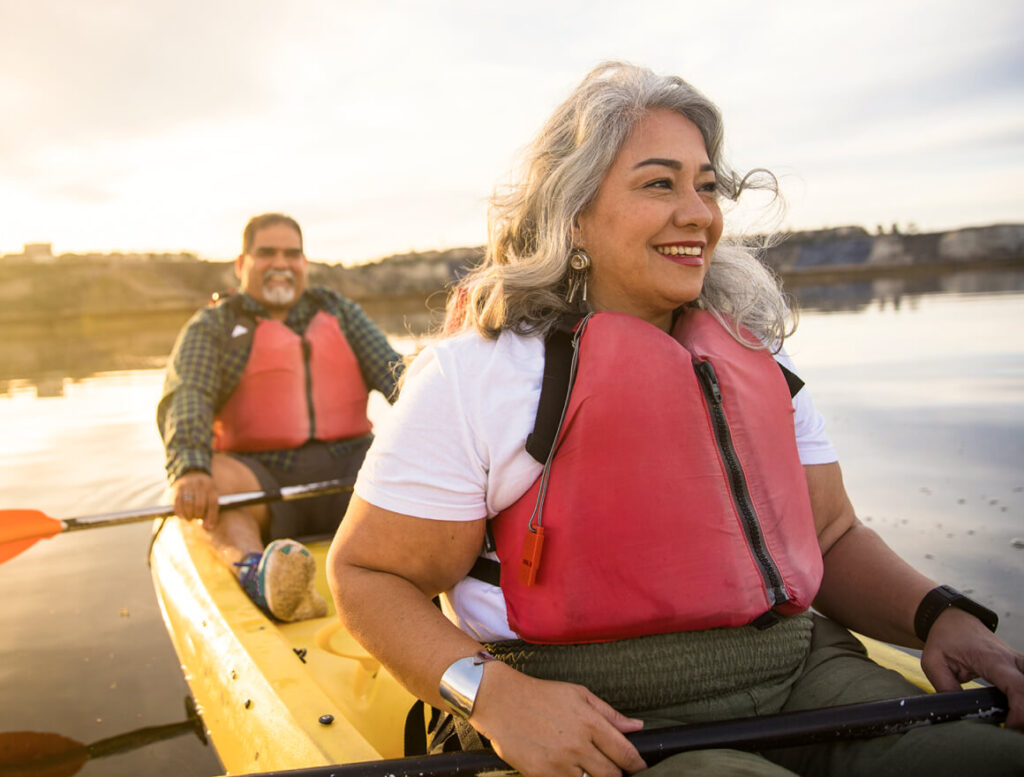 Smiling couple kayaking together on a river at sunset